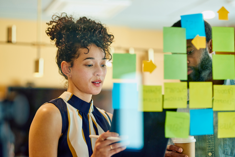 Woman and man mapping out a project on a transparent glass wall.
