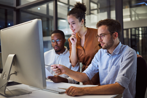 Two men and a woman looking at a computer screen together.