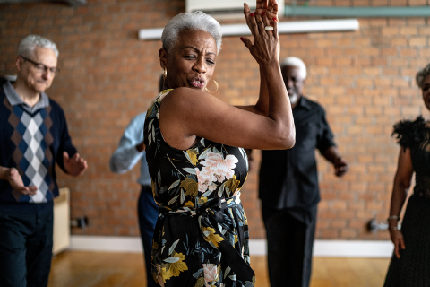 Older woman dancing in the middle of a group of older adults.