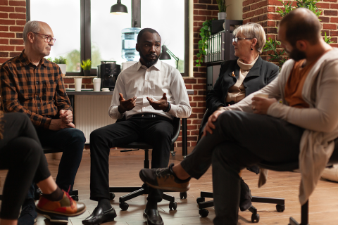 Person at therapy session having discussion about addiction with three other people.